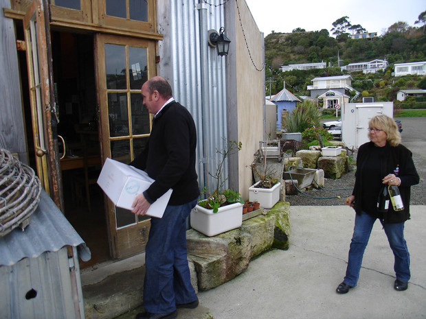 A Fine Wine delivery of Sam Neill's "Two Paddocks" vintages being received, and followed closely, by Fleur Sullivan at her famous seafood restaurant, "Fleur's Place", at Moeraki, a tiny fishing village in North Otago New Zealand. Mark Fields, manager of Neill's wine-growing operation in Central Otago, leads in with a case of "Socialist Chardonnay", a tongue-in-cheek label of Sam's, but nonetheless a very fine wine, especially to accompany superbly prepared seafood. 