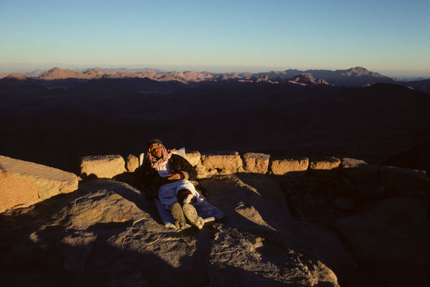 Bedouin guide resting in walled area on summit of Mt Sinai at sunset.