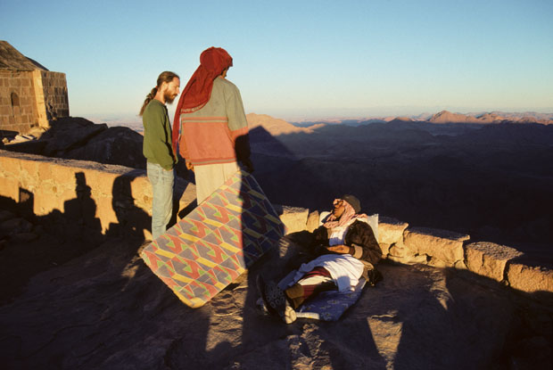 Visitor and Bedouin guides in walled area, including Christian Chapel (left-picture), on summit of Mt Sinai at sunset.
