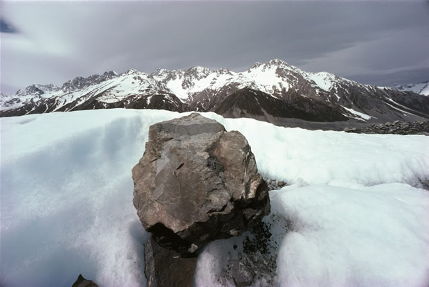 Tasman Glacier: moraine boulder being carried southwards on mid-glacier ice. Liebig Range in background.