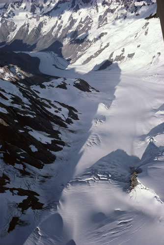 Tasman Glacier: westward view of middle and lower neve, with Tasman Saddle Hut (red) on rocky outcrop at lower right. Malte Brun range casts a shadow from the left; the Main Divide is seen in the distance.