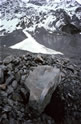 Tasman Glacier: facetted boulder on surface moraine of lower reaches of glacier. Lateral moraine with fan-shaped ice-spill from Main Divide of Southern Alps in distance.